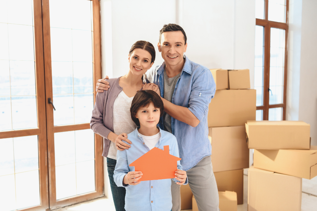 Father, mother and son in new apartment with cardboard boxes near doors